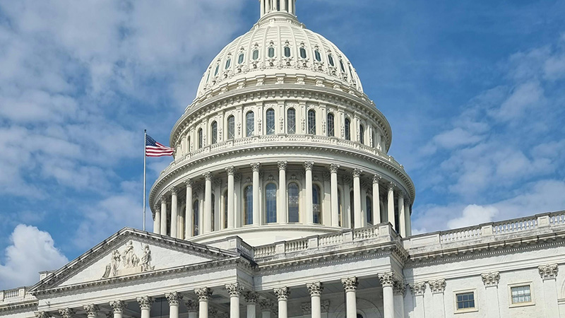 A view of the US Capitol building with the red, white, and blue American flag