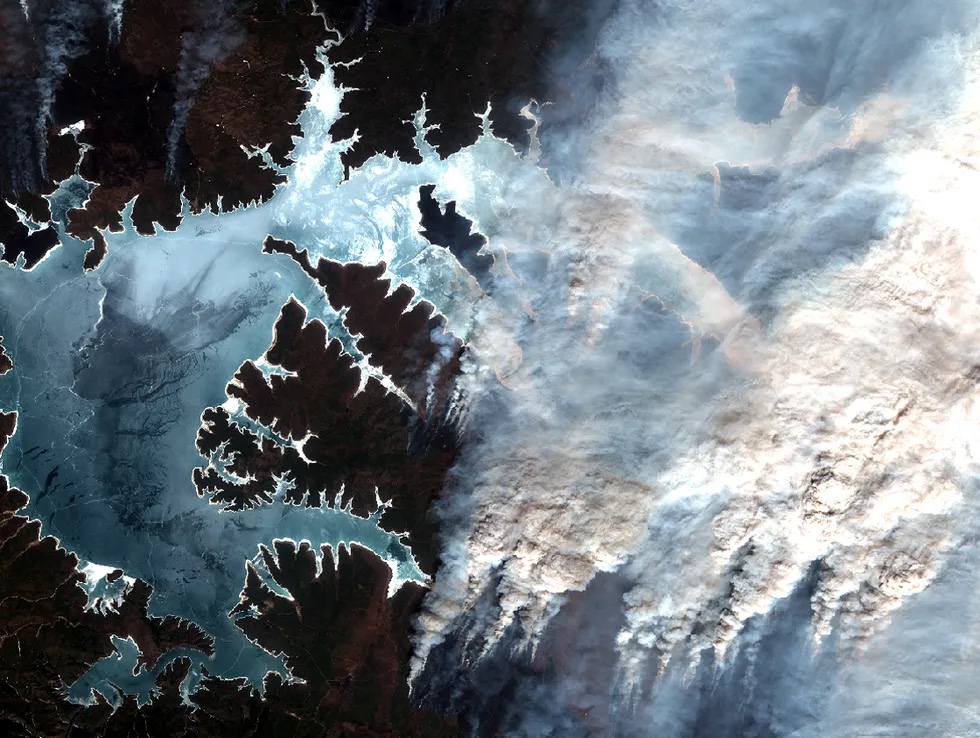 Image of land from space with smoke blowing over it
